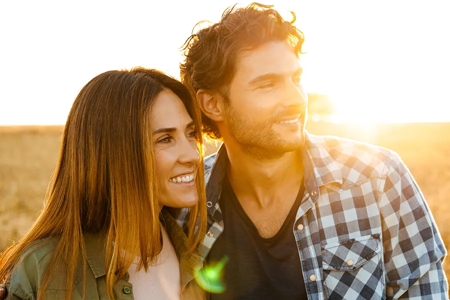 A healthy couple looking out over a cornfield in the fall with the sunset behind them. Get allergy treatment services from Allen Green, M.D. of Center for Optimum Health in Los Angeles.
