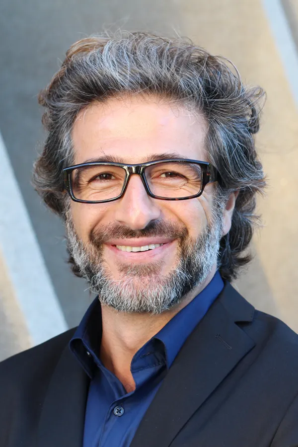 A man with glasses, salt and pepper hair and a beard smiling because he received treatment for andropause and low testosterone from Allen Green, M.D. of Center for Optimum Health in Los Angeles.