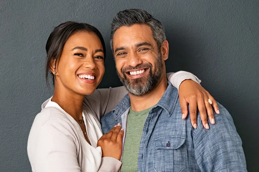 Bioidentical-Hormone-Therapy-Doctor A middle-aged couple with their arms around each other standing against a gray background and smiling, happy with the bioidentical hormone therapy they received from Allen Green, M.D. of Center for Optimum Health in Los Angeles.