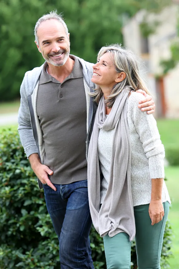 Bioidentical-Hormone-Therapy-Treatment A mature couple in gray toned clothes and jeans walk happily outside, happy with their successful bioidentical hormone treatments from Allen Green, M.D. of Center for Optimum Health in Los Angeles.
