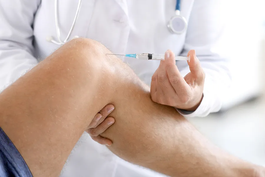 A doctor injects biopuncture therapy into the knee of a man with joint pain. Get biopuncture therapy from Allen Green, M.D. of Center for Optimum Health in Los Angeles.