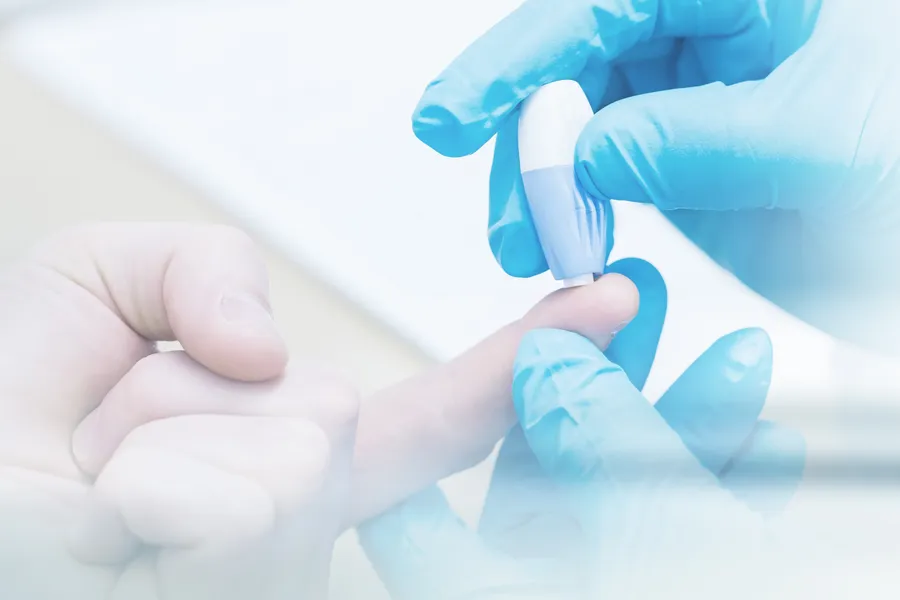 A doctor's gloved hand pricks a patients finger with to measure blood sugar, symbolizing diabetes treatment from Allen Green, M.D. of Center for Optimum Health in Los Angeles.