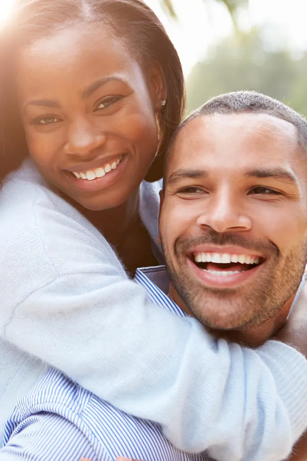 A woman riding on a man's back, both smiling due to help with erectile dysfunction from Allen Green, M.D. of Center for Optimum Health in Los Angeles.