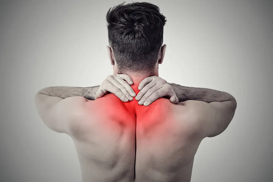 An image from behind of a man suffering from Fibromyalgia rubbing an area illustrated red with pain in his shoulders and neck . Get fibromyalgia treatment from Allen Green, M.D. of Center for Optimum Health in Los Angeles.