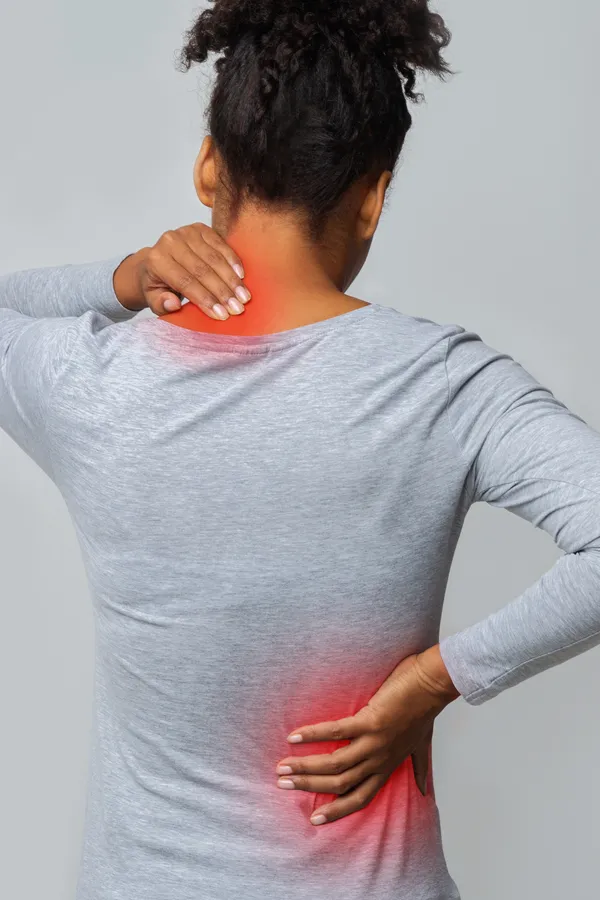 An image from behind of a woman suffering from Fibromyalgia holding her hands on her neck and lower back. Get fibromyalgia treatment from Allen Green, M.D. of Center for Optimum Health in Los Angeles.