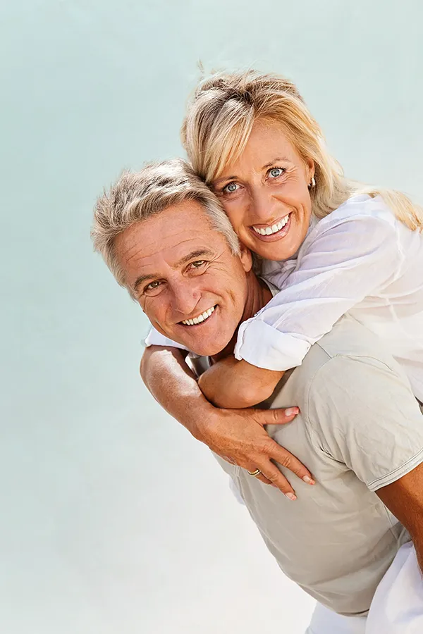 A happy mature couple having fun - the husband is carrying his wife on his back. Get treatment for food allergies from Allen Green, M.D. of Center for Optimum Health in Los Angeles.