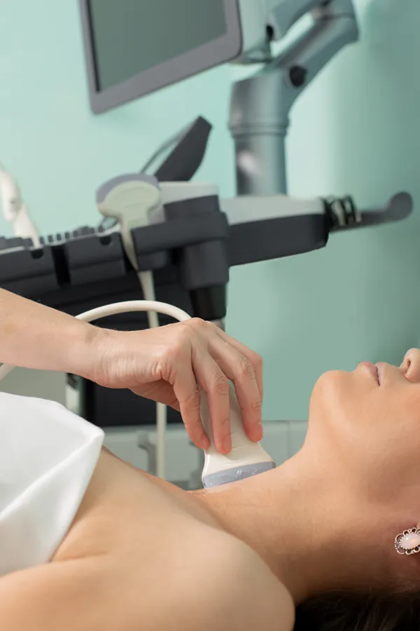 A woman gets a thyroid scan from a doctor in a clinic. Get help with Hashimoto's Thyroiditis from Allen Green, M.D. of Center for Optimum Health in Los Angeles.