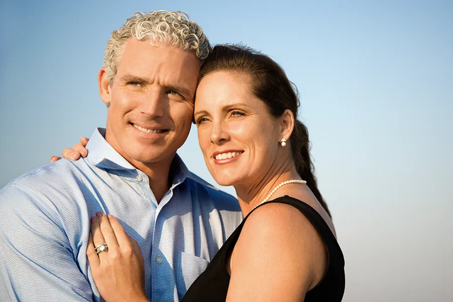 A middle-aged caucasian couple embraces in the sunshine, happy with the healthy aging peptide treatments from Allen Green, M.D. of Center for Optimum Health in Los Angeles