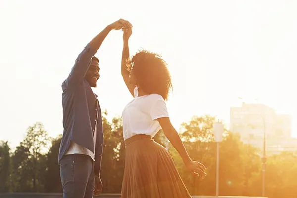A black couple dances outside lit by the sunset. Get immunotherapy for autoimmune diseases from Allen Green, M.D. of Center for Optimum Health in Los Angeles.