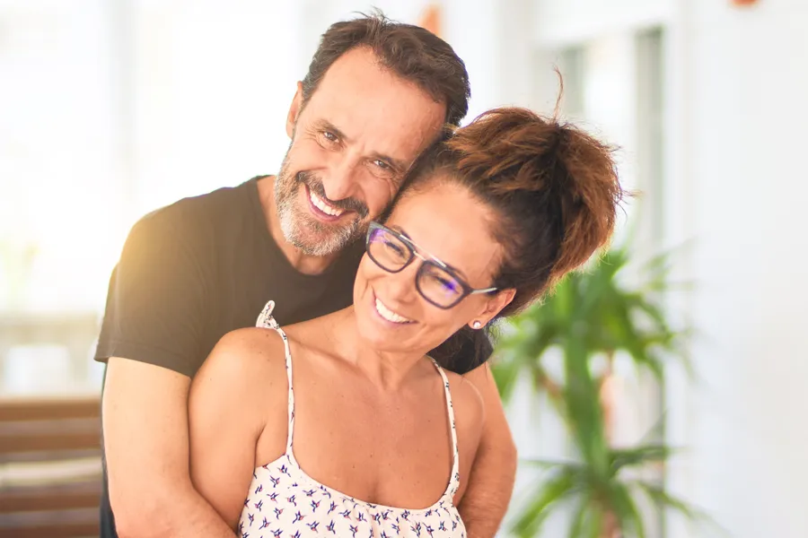 A happy couple embrace in their sunroom. Get LDI allergen injection therapy from Allen Green, M.D. of Center for Optimum Health in Los Angeles.
