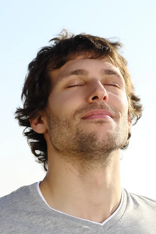 A brown-haired man closes his eyes and breathes in fresh air with his face turned up to the sky. Get treatment for Lupus from Allen Green, M.D. of Center for Optimum Health in Los Angeles.