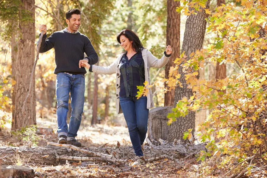 A couple happily hiking in the forest in fall. Get treatment for Lyme Disease from Allen Green, M.D. of Center for Optimum Health in Los Angeles.