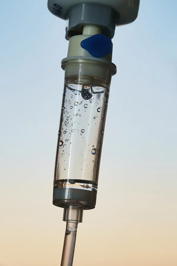 Close-up of an IV drip in front of a dusk sky. Get ozone IV therapy from Allen Green, M.D. of Center for Optimum Health in Los Angeles.