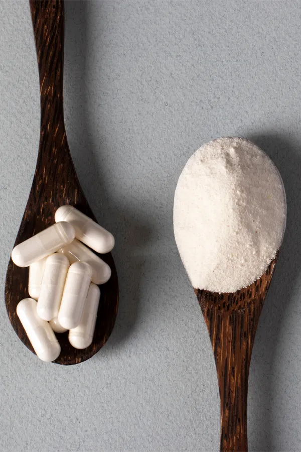 Two wooden spoons on a table, on with white powder and one with capsules, representing peptide therapy from Allen Green, M.D. of Center for Optimum Health in Los Angeles.