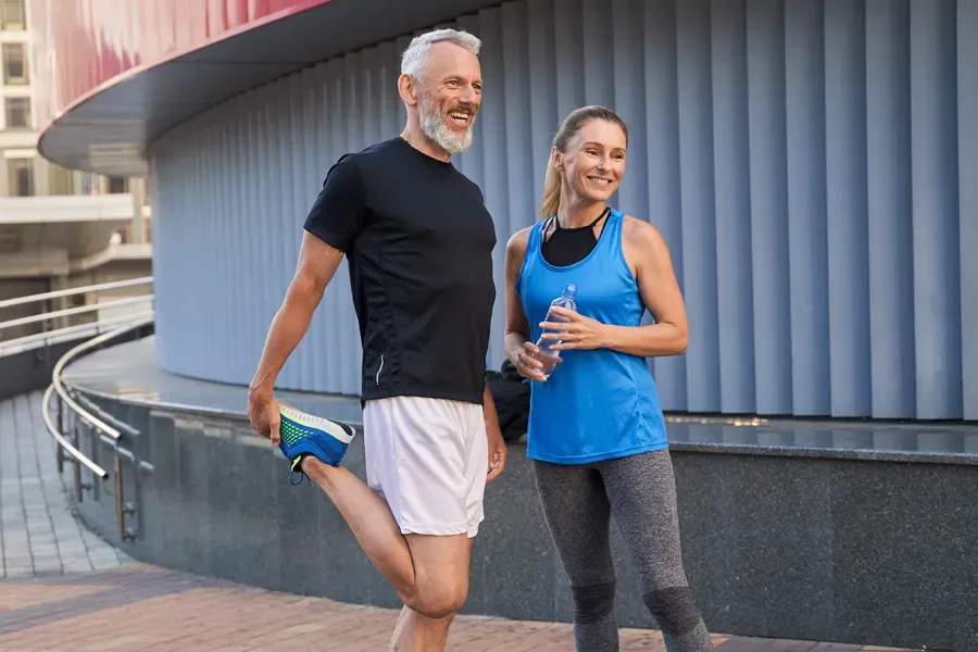 A middle-aged couple happily stretch and prepare for exercise after receiving effective peptide therapy for healing and recovery from Allen Green, M.D. of Center for Optimum Health in Los Angeles.