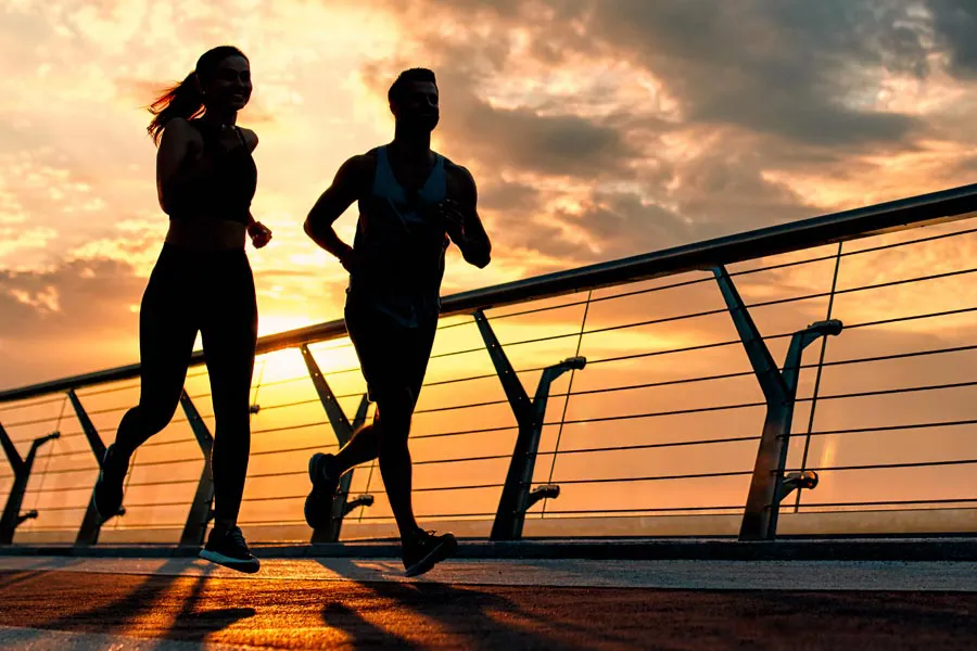 Performance-Enhancing-Peptides-Doctor A couple jogging on a bridge at sunrise, representing performance enhancing peptide therapy from Allen Green, M.D. of Center for Optimum Health in Los Angeles.