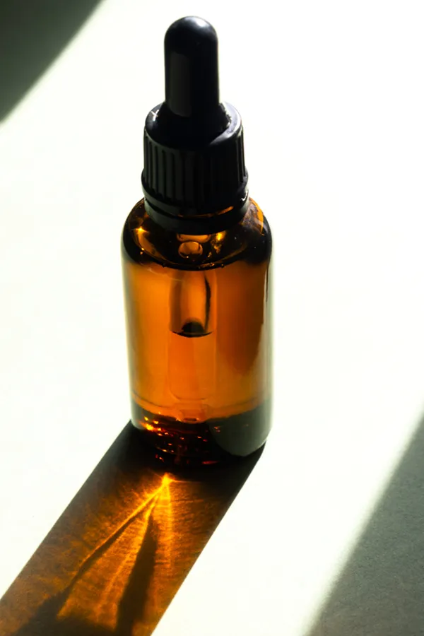 Performance-Enhancing-Peptides-Treatment A brown dropper bottle on a table lit by sunlight, representing performance enhancing peptide treatment from Allen Green, M.D. of Center for Optimum Health in Los Angeles.
