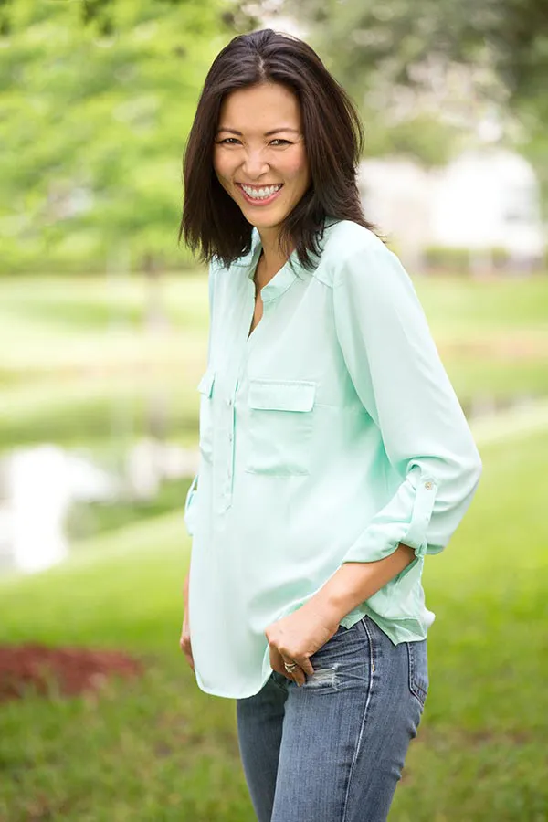 Perimenopause-Treatment A middle-aged brunette woman in a light green button-up shirt stands outside smiling, happy with her perimenopause treatment from Allen Green, M.D. of Center for Optimum Health in Los Angeles.