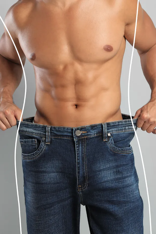 A strong shirtless man in jeans holds the waistlines of his too-big jeans to show the success of semaglutide weight loss from Allen Green, M.D. of Center for Optimum Health in Los Angeles.